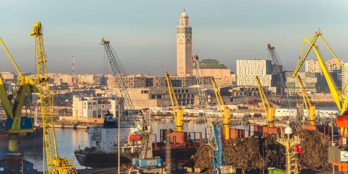 Casablanca, Morocco - December 8, 2016: The scene early in the morning with harbor cranes, elevators, ships and cargoes in the seaport of Casablanca, Morocco. The Hassan II Mosque in in the background.